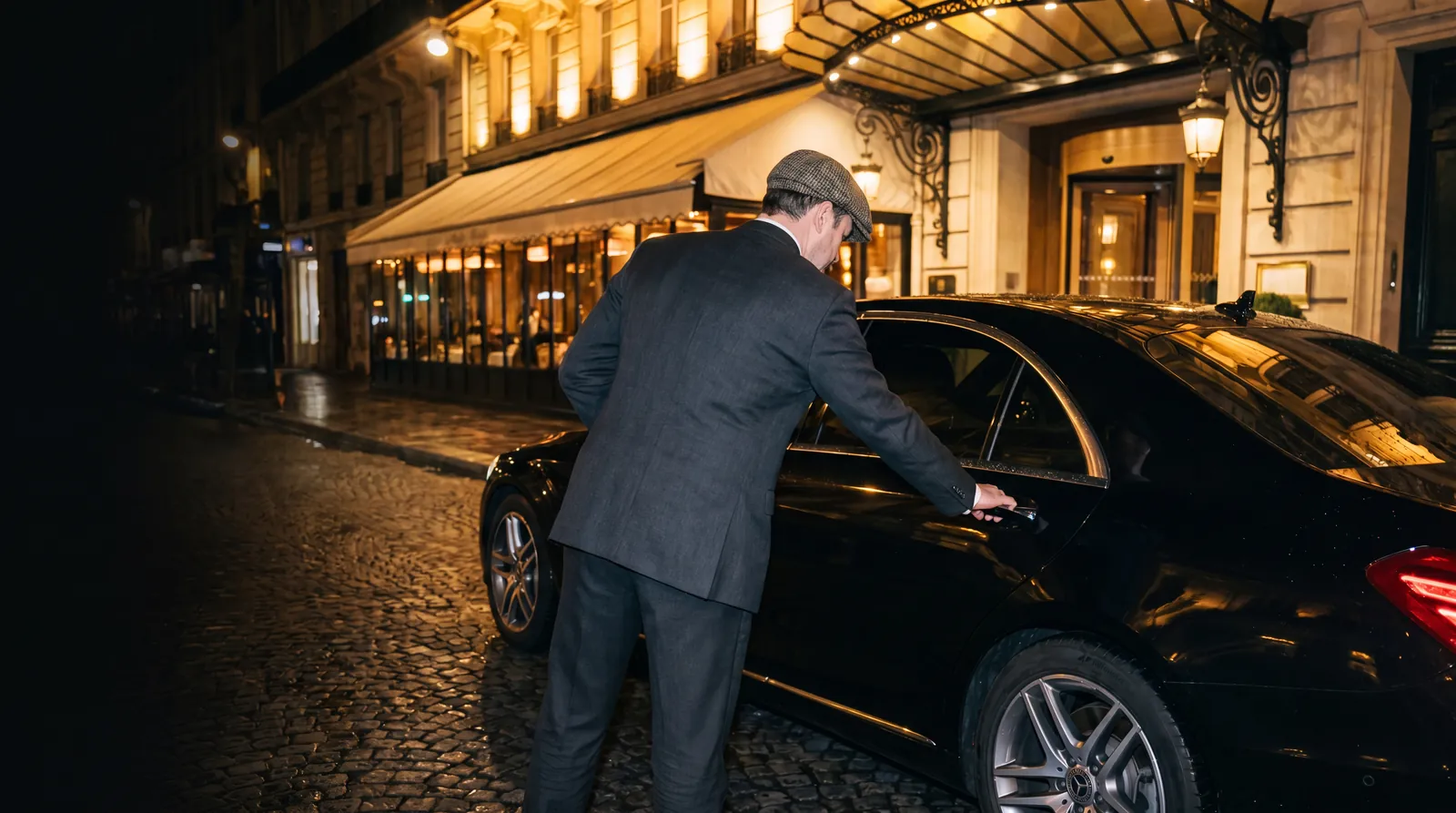 Voiturier en tenue accueillant un client devant un établissement parisien